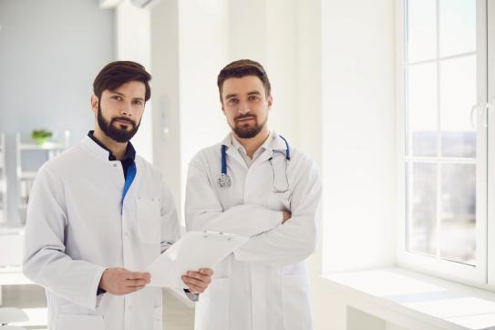 Zwei Ärzte stehen selbstbewusst in einer Praxis